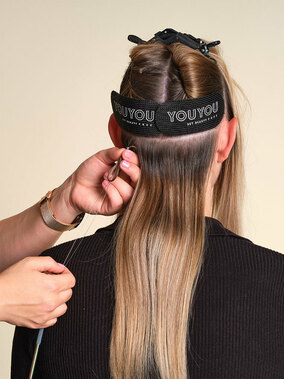 YOUYOU Tressen, Step 2: Haarsträhne mit dem Loop durch den Mikroring ziehen und den Ring zum Haaransatz hochschieben. Er sollte mittig sitzen, sodass links und rechts genug Platz zum Nähen ist. Mit der Zange andrücken. (&copy; YOUYOU Hair)