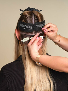 Y0UYOU Tressen, Step 5: Gekürzte Tresse mit YOUYOU<br />
Clips fixieren und mit einem<br />
durchgehenden Faden links und<br />
rechts der Mikroringe annähen.<br />
Dabei eine gebogene Nadel<br />
verwenden. (&copy; © Great Lengths / YOUYOU)